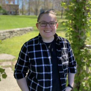 Carolyn Rau wearing eye glasses and a black and white checked shirt, standing outdoors